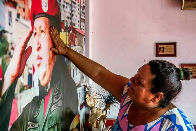 A woman touches a poster of the late President Hugo Chavez inside Santo Hugo Chavez del 23 chapel, at 23 de Enero community in Caracas on February 27, 2015. Next March 5, marks the second anniversary of Chavez’s death. The eternal proclaimed commander who directed the South American nation for more than a decade has left a void that neither his political heirs, nor opponents have been able to fill. AFP PHOTO/FEDERICO PARRA
