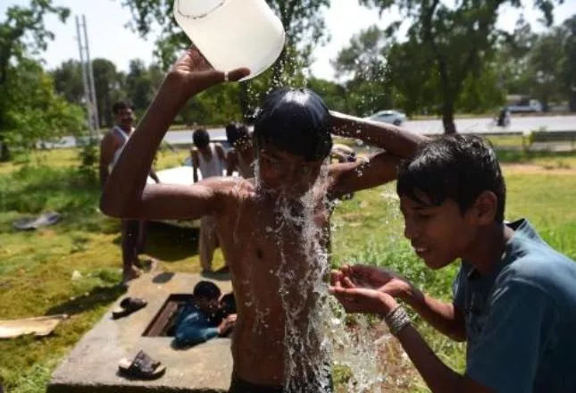 Pakistani youth cool themselves with water during a heat wave in Islamabad on June 21, 2015. At least 17 people have died as a heat wave has gripped the country, local media reported.  AFP PHOTO /  Farooq NAEEM