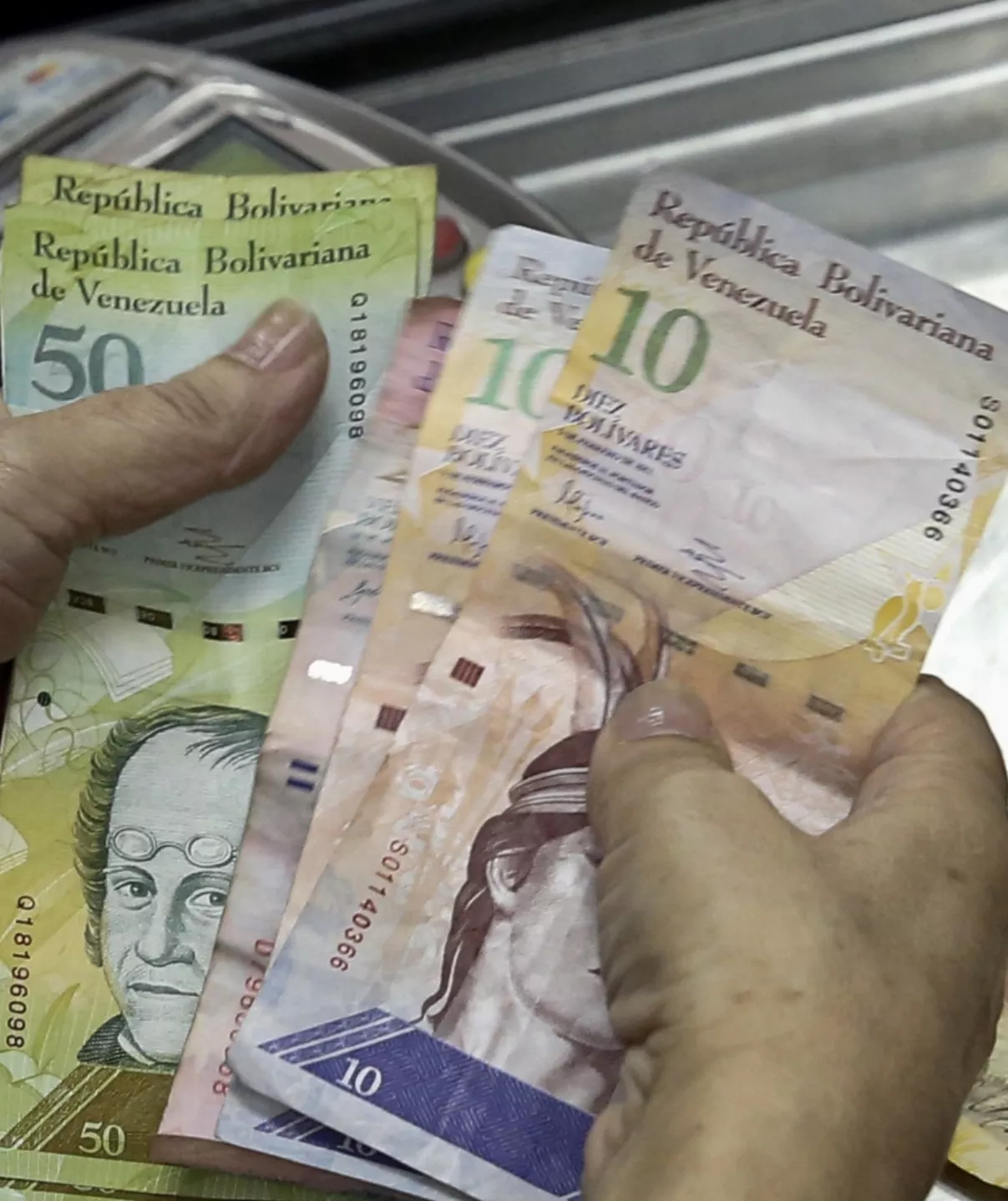 A cashier counts Venezuelan bolivar notes at a supermarket checkout line in Caracas