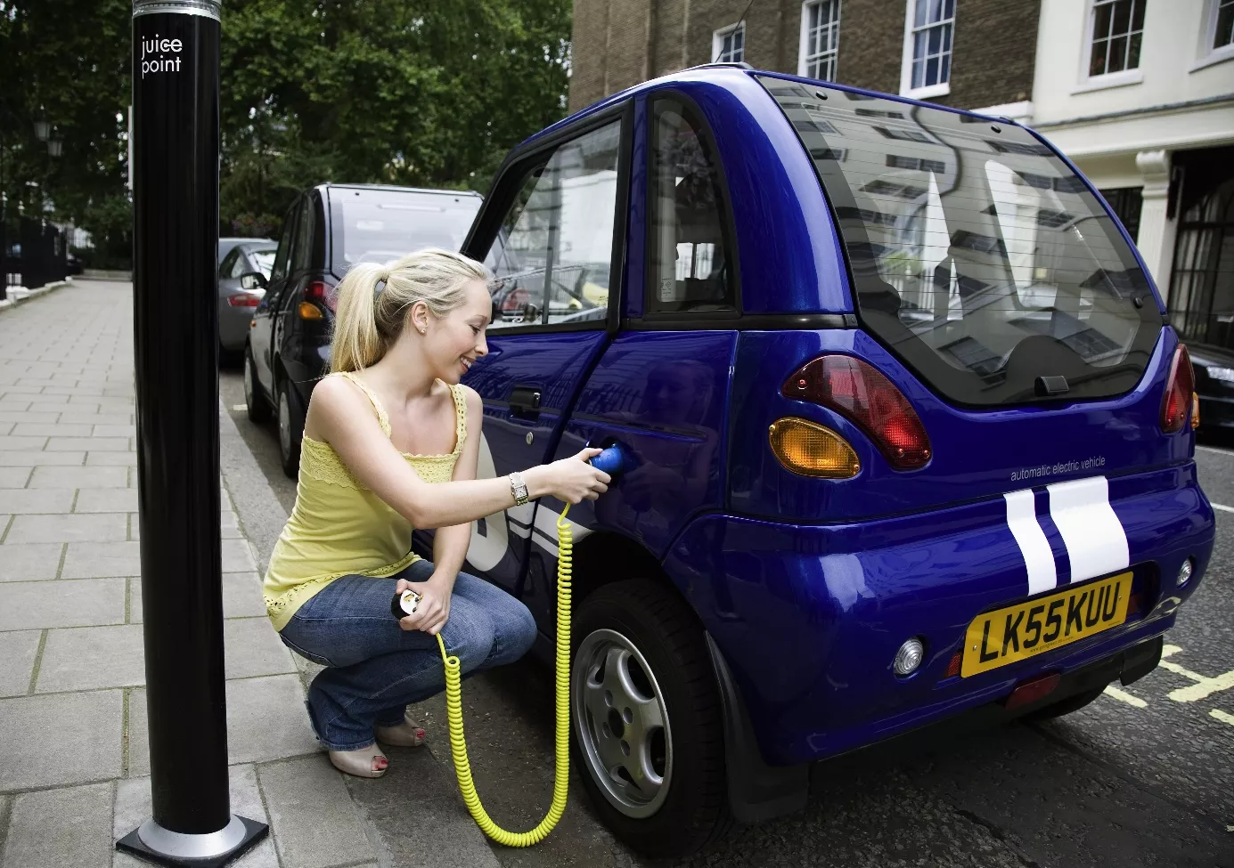 Young woman charging electric car