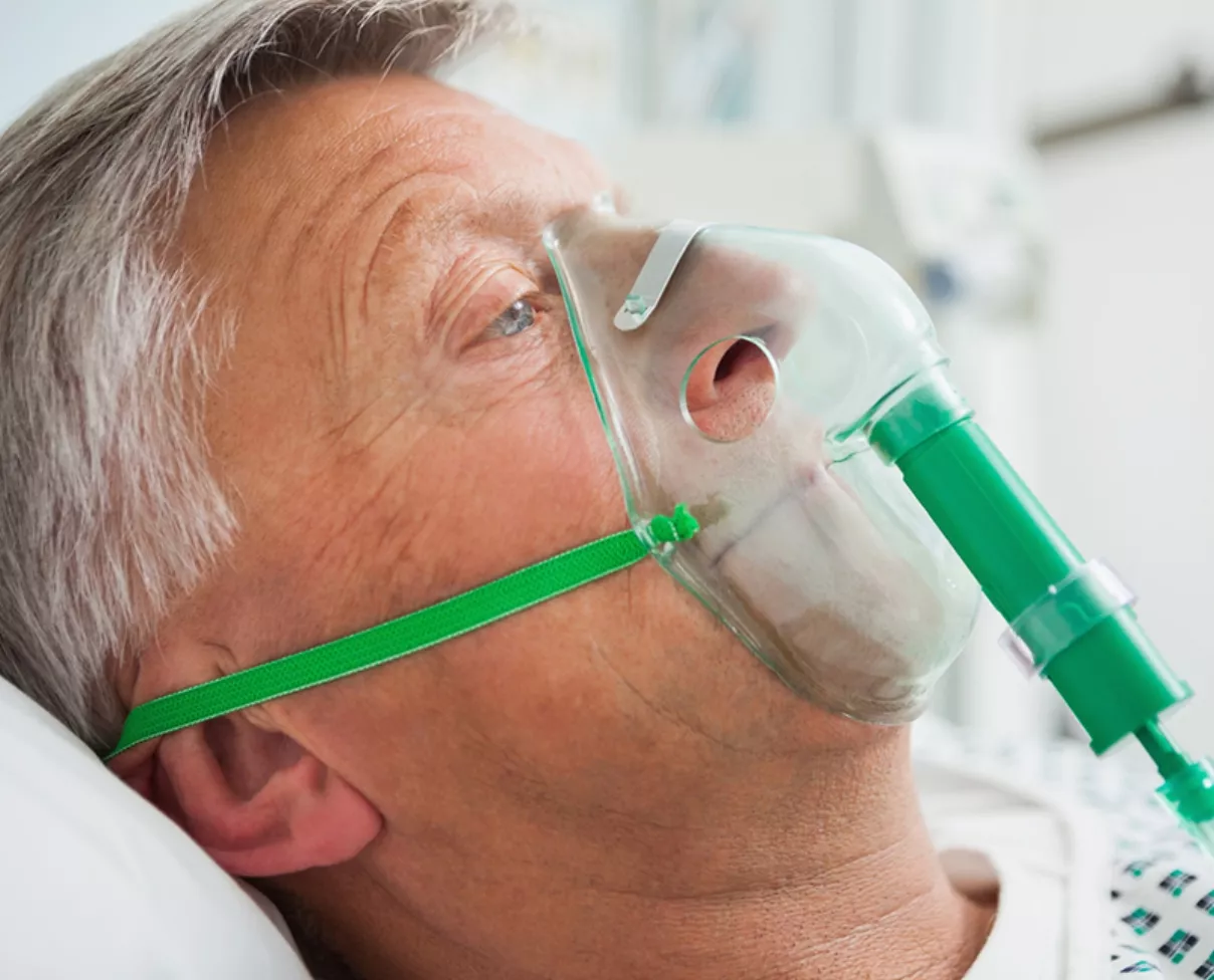 Man in bed with oxygen mask in hospital