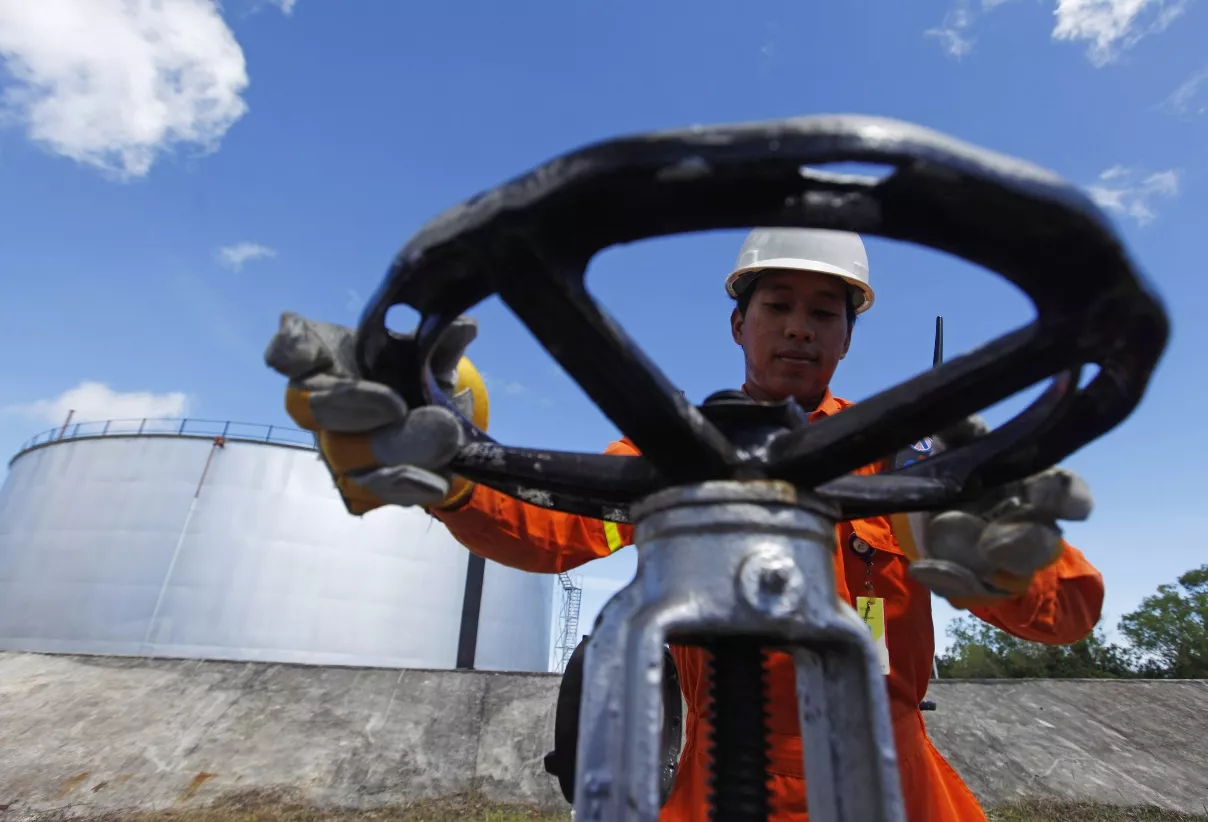 File photo of PT Pertamina worker opening a gauge near crude oil tanks on Bunyu island