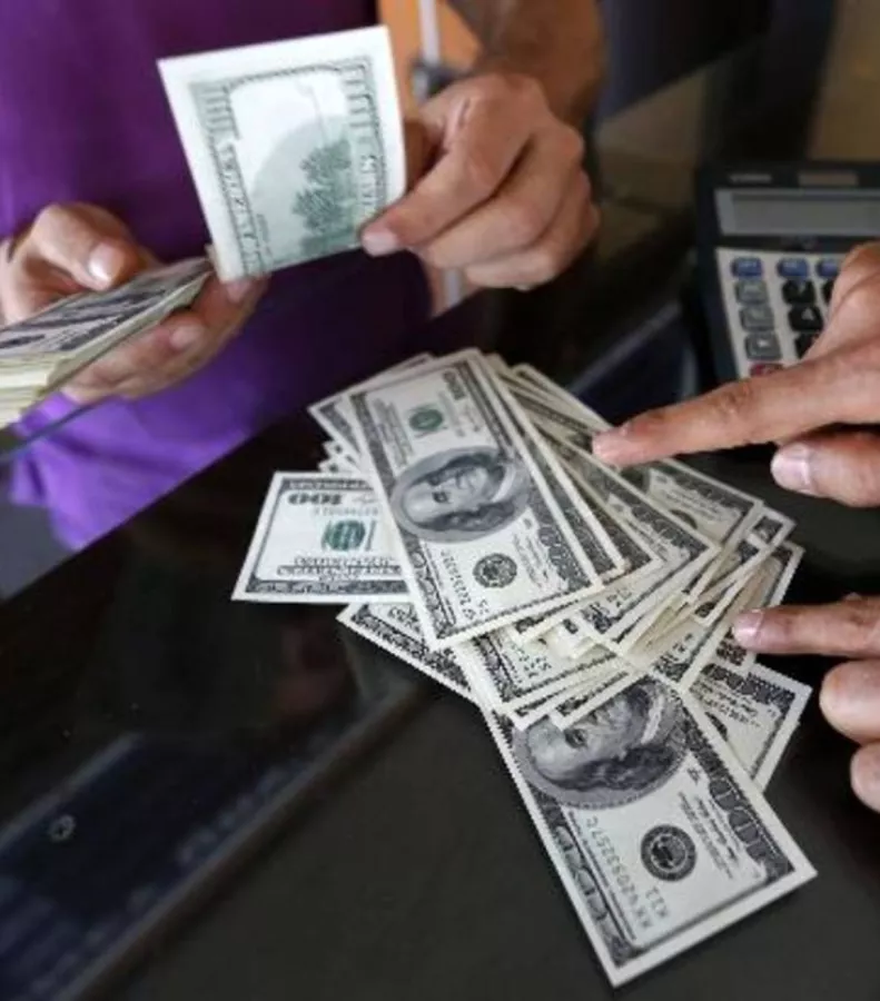 A money changer sells U.S. dollars to a customer in the border city of Hatay
