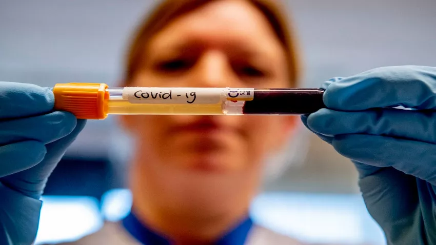 A lab technician holding a test tube that contains blood