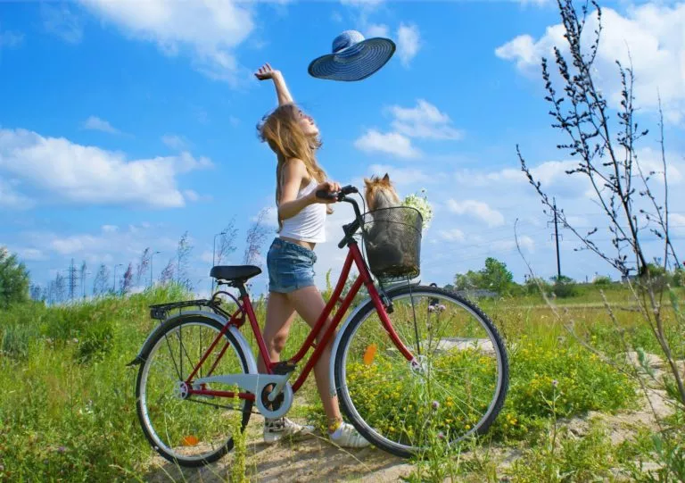 linda-chica-disfruta-un-día-soleado-a-orillas-de-la-ciudad-con-mascota-en-la-bicicleta-768×541
