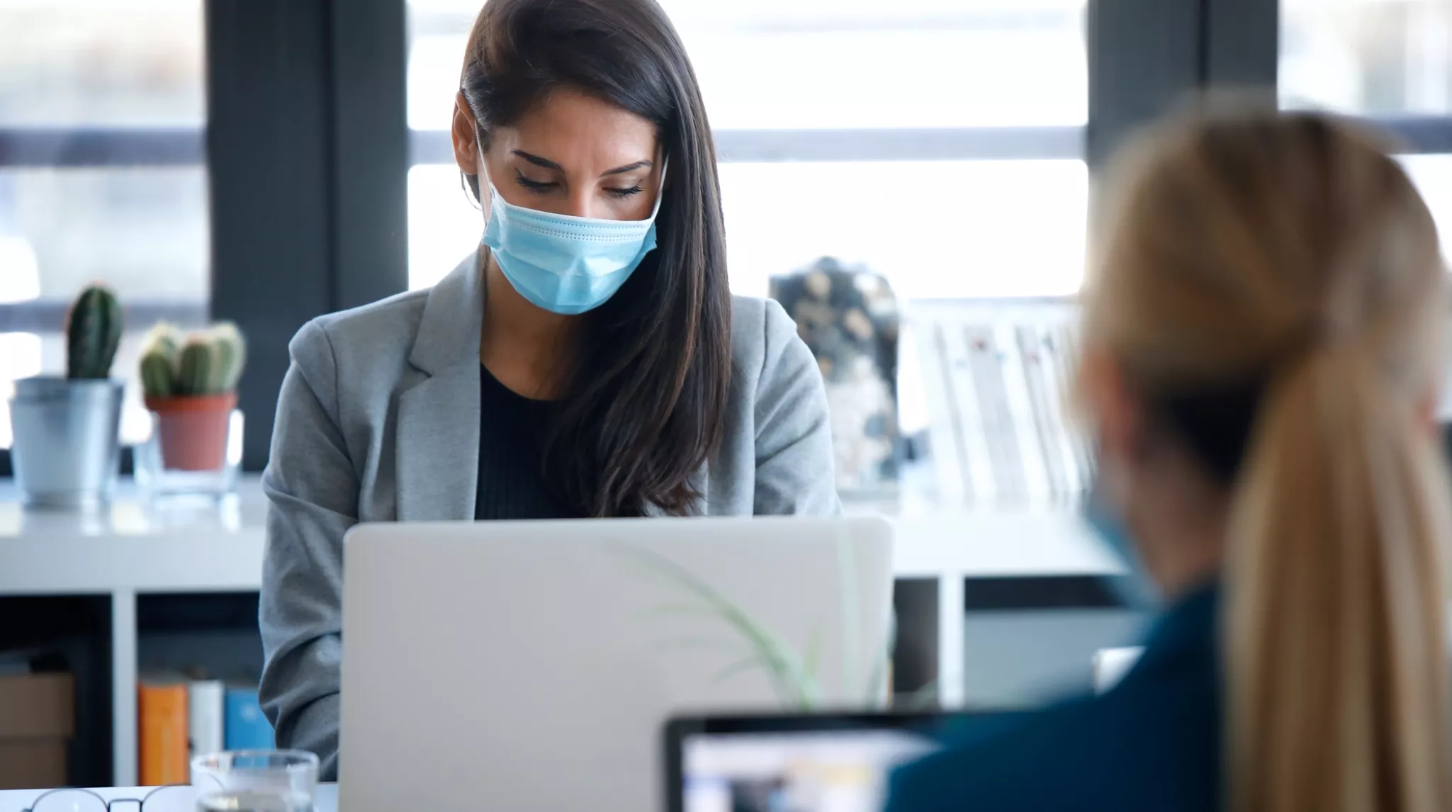 Two business women wearing a hygienic face mask while work with