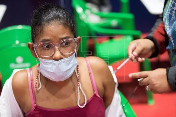Joven recibe dosis de vacuna contra coronavirus.