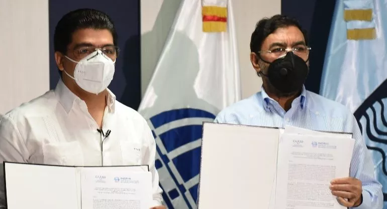 Directores de INDRHI y CAASD muestran el documento.