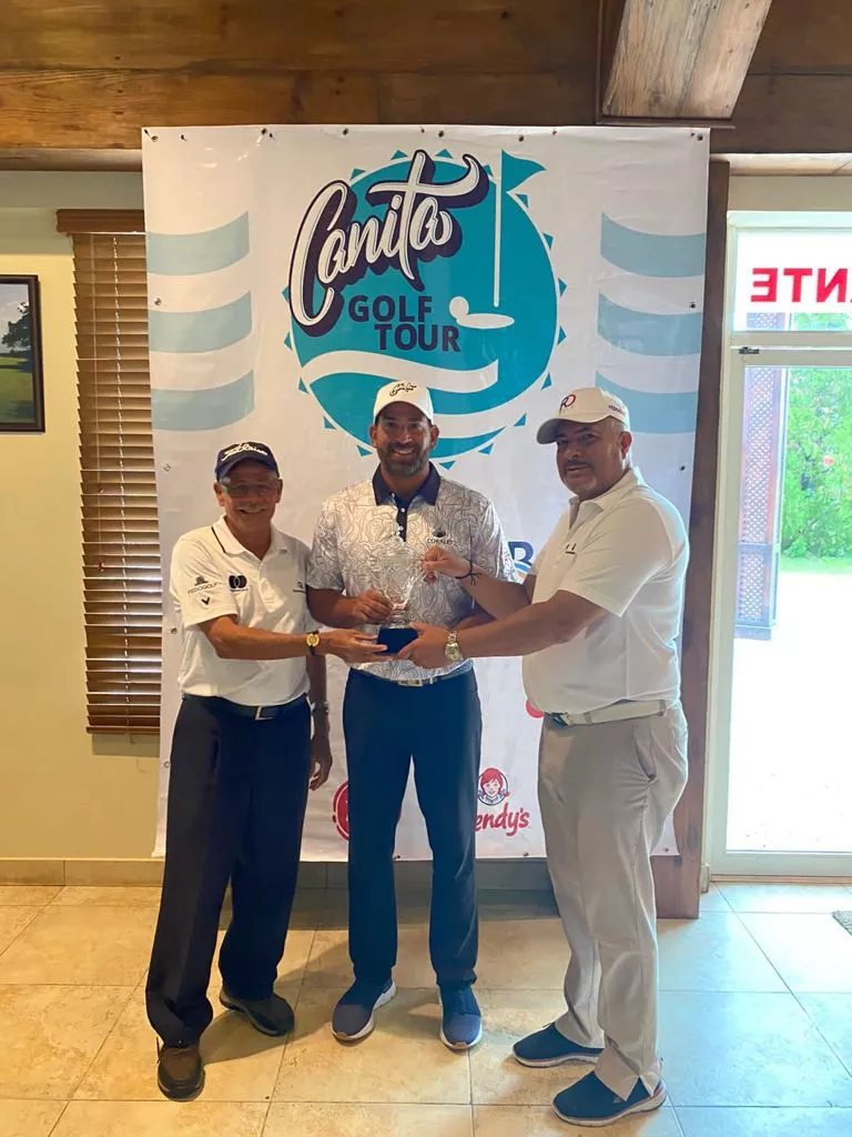 Hiram Silfa (centro), recibe el trofeo de campeón por parte de Rafael Canario y Luis Jose Placeres, de Fedogolf