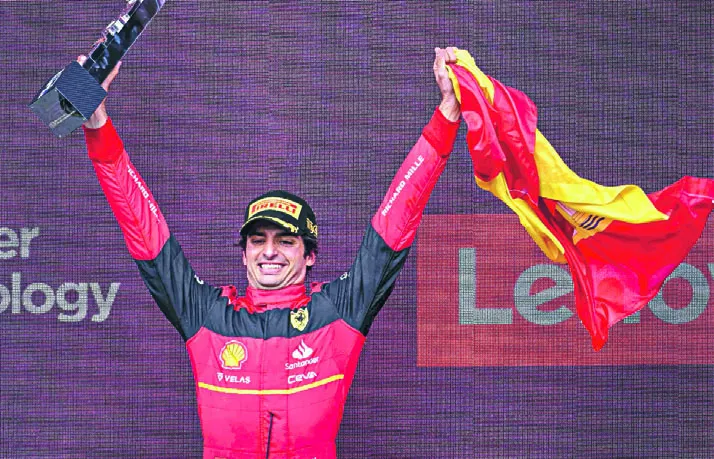 El piloto Carlos Sainz celebra el triunfo en Silverstone, con la bandera española en alto.