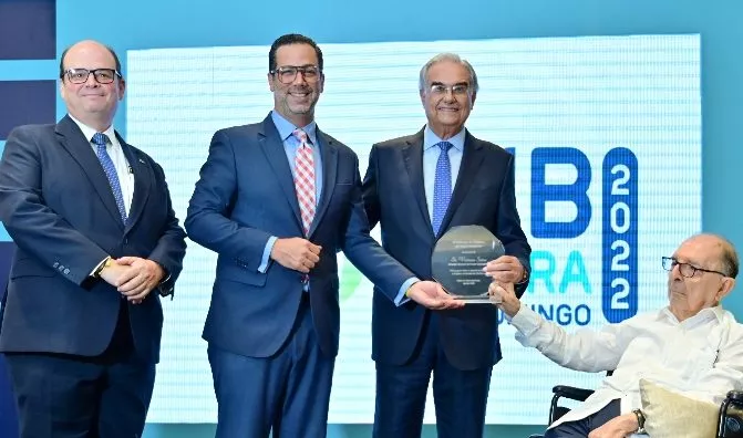 Miembros de la Cámara de Comercio  entregan el reconocimiento.