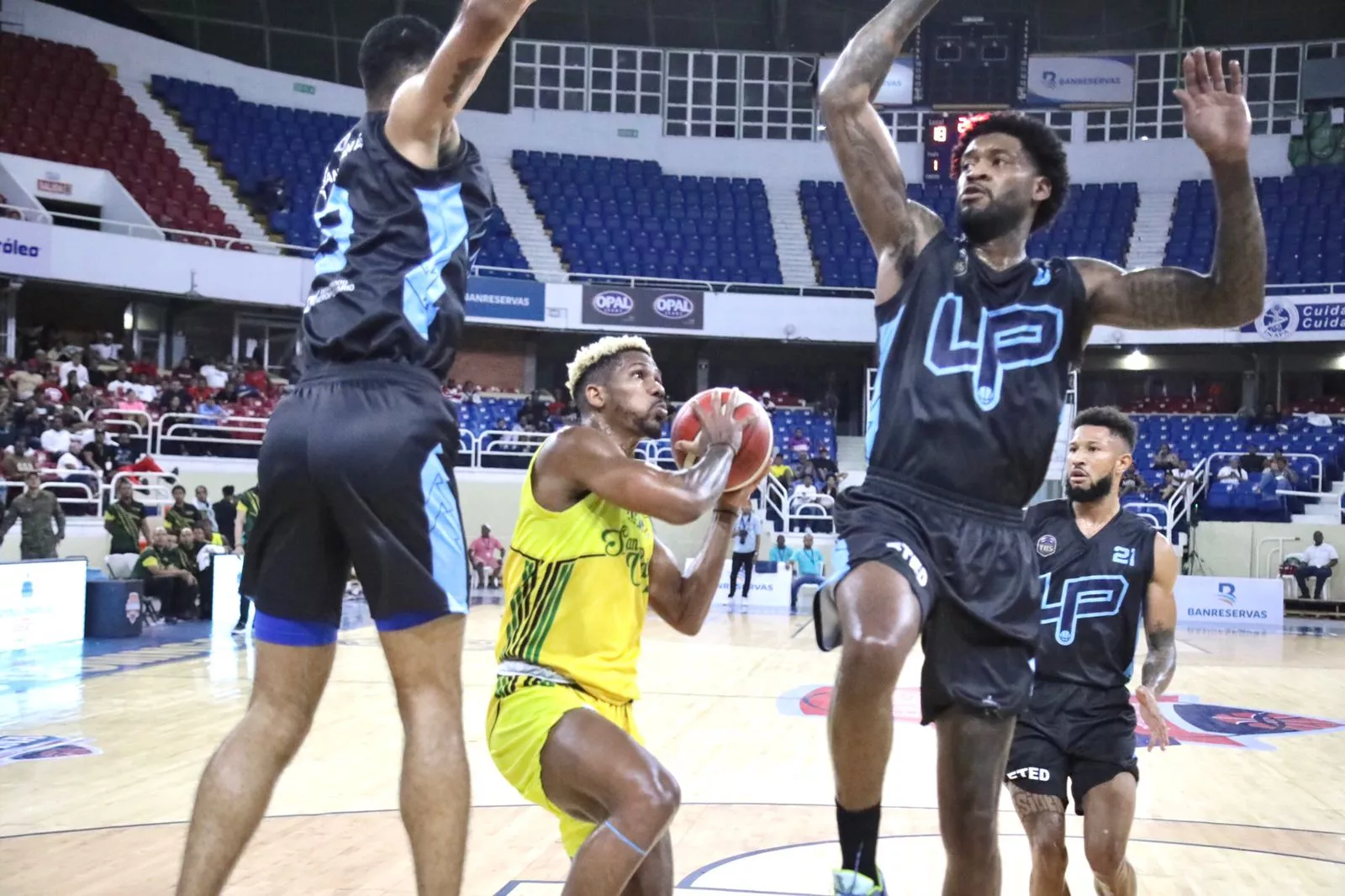 Yeison Colomé, de San Carlos, entre los jugadores de Los Prados, Anyeuri Castillo y Perry Jones III.