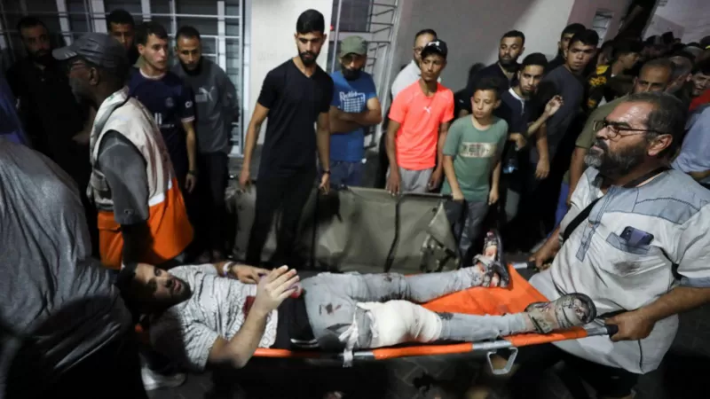 Un hombre herido es llevado en camilla para recibir asistencia después de que un ataque impactara en el hospital Bautista Al-Ahli.