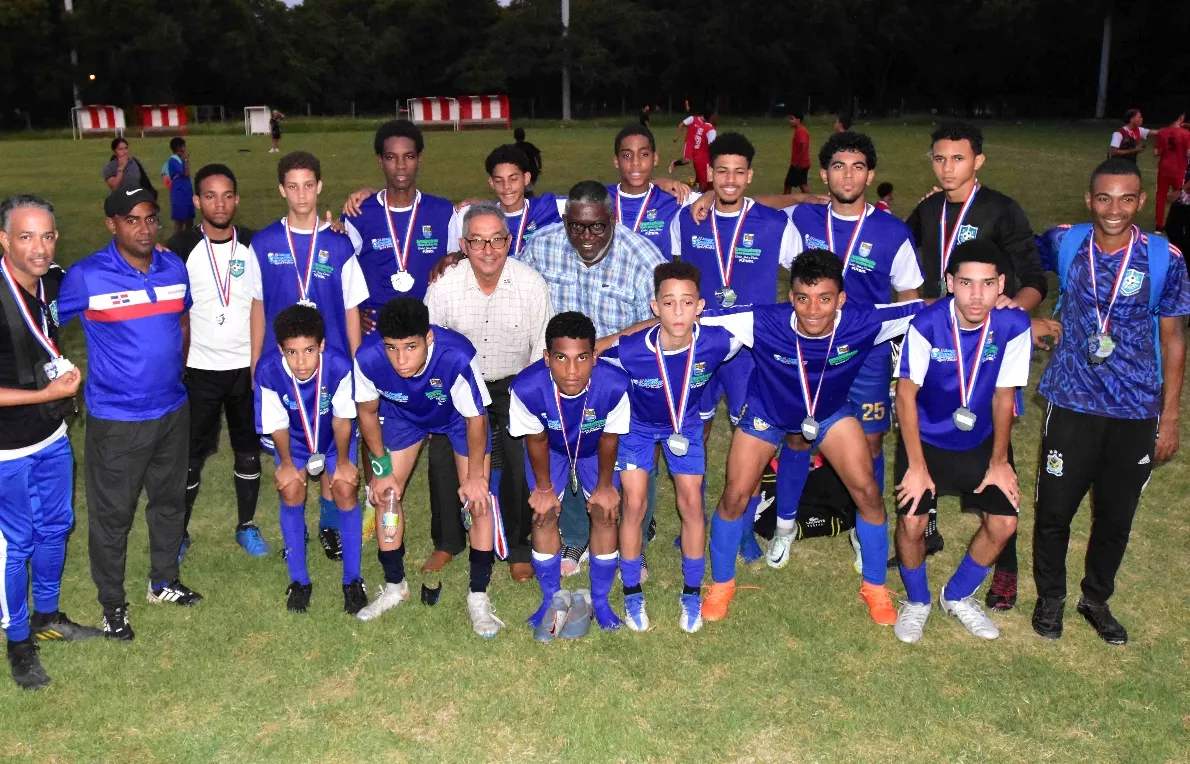 Ángel Rivas, director técnico de los IV Juegos Deportivos Municipales de Santo Domingo Este, aparece rodeado por los jugadores del equipo ganador de medalla de plata.