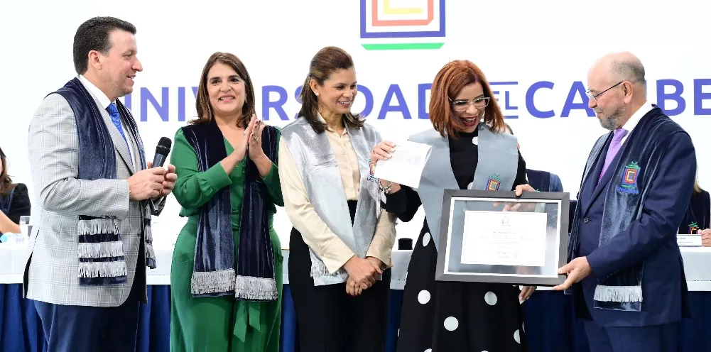Las autoridades académicas entregan un título a una de las graduandas.