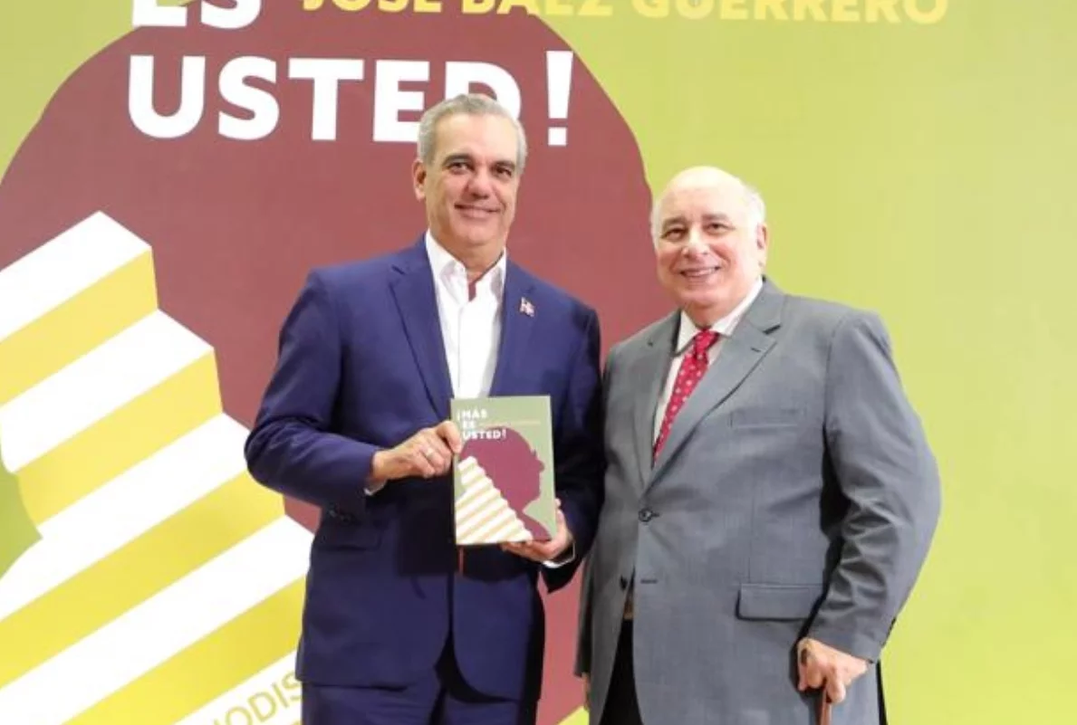 El presidente Luis Abinader muestra, junto Báez Guerrero, un ejemplar de las memorias.