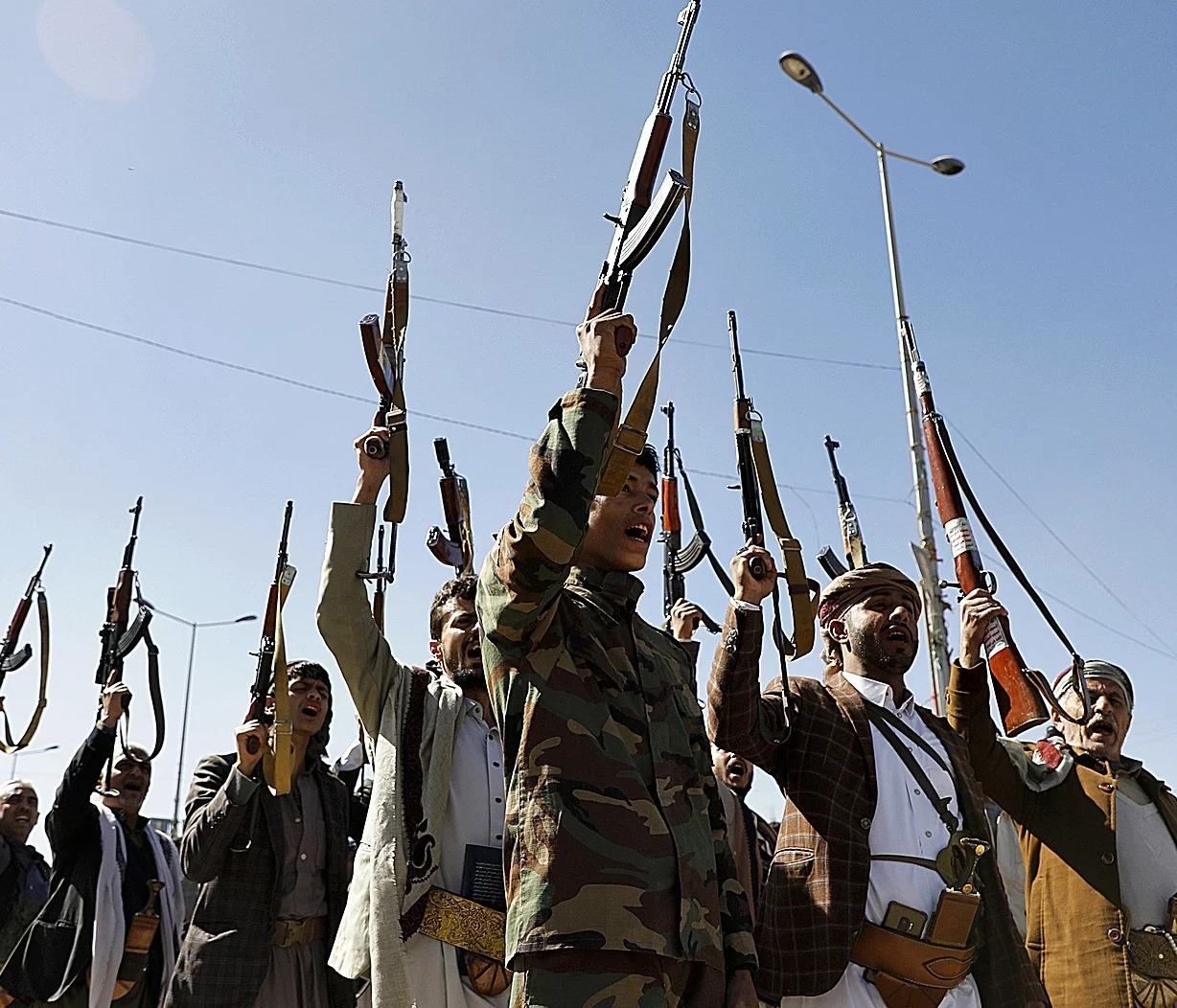 Newly recruited Houthi fighters hold up a weapons and chanting slogans