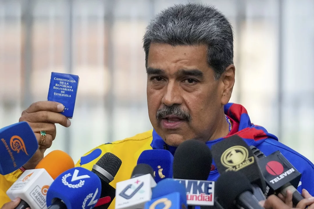 El presidente Nicolás Maduro muestra una miniedición de la constitución de Venezuela después de votar en las elecciones presidenciales.