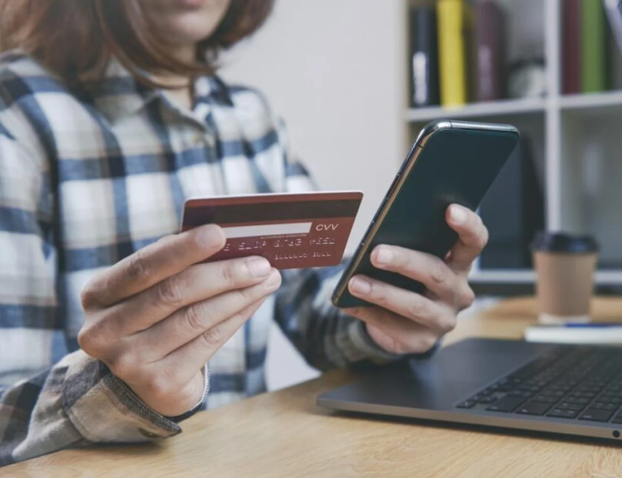 Young woman holding credit card and using smart phone buying onl