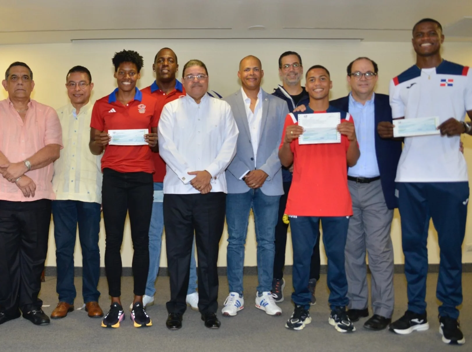 Marileidy Paulino, Yunior Alcántara y Cristian Pinales reciben sus cheques de las manos de las autoridades deportivas.