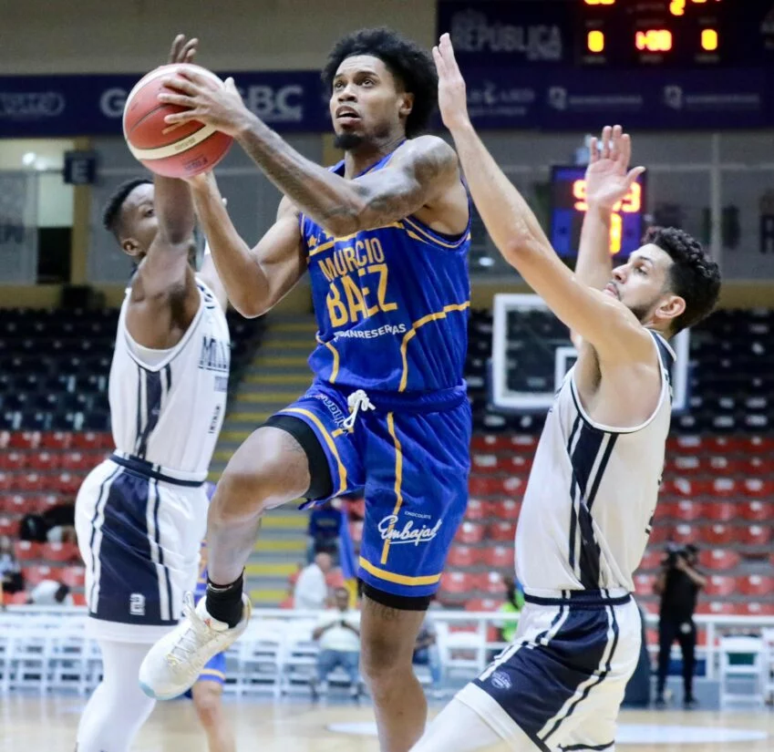 Jhery Matos, del club Mauricio Báez, intenta completar la anotación entre los jugadores de El Millón, Andrés Martínez y Brayan Polanco.