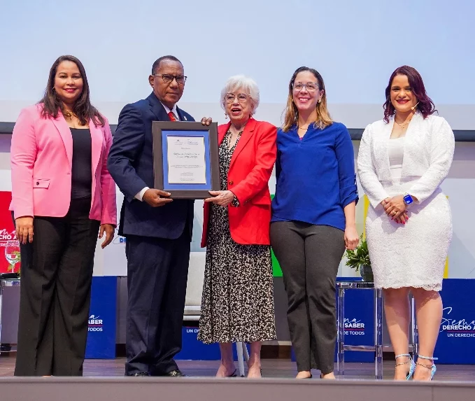 Milagros Ortiz Bosch entrega la distinción  al subdirector del Inespre, Obispo de los Santos.