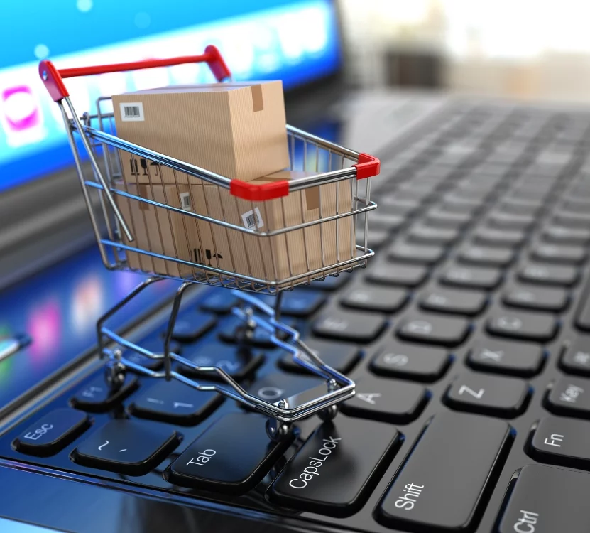 E-commerce. Shopping cart with cardboard boxes on laptop.