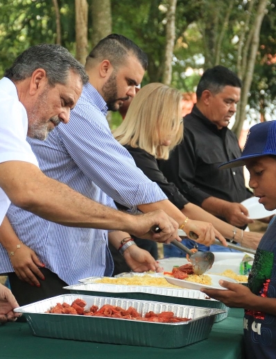 El Comisionado  Junior Noboa sirve alimentos a los atletas.