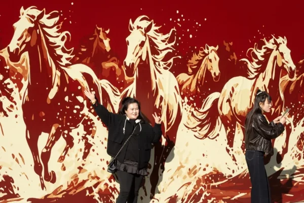 Unas mujeres posan ante un mural de caballos, hoy en Pekín.