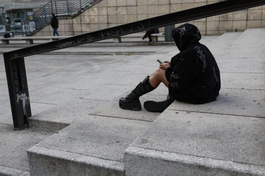 Una joven mira su teléfono móvil sentada en unas escaleras.